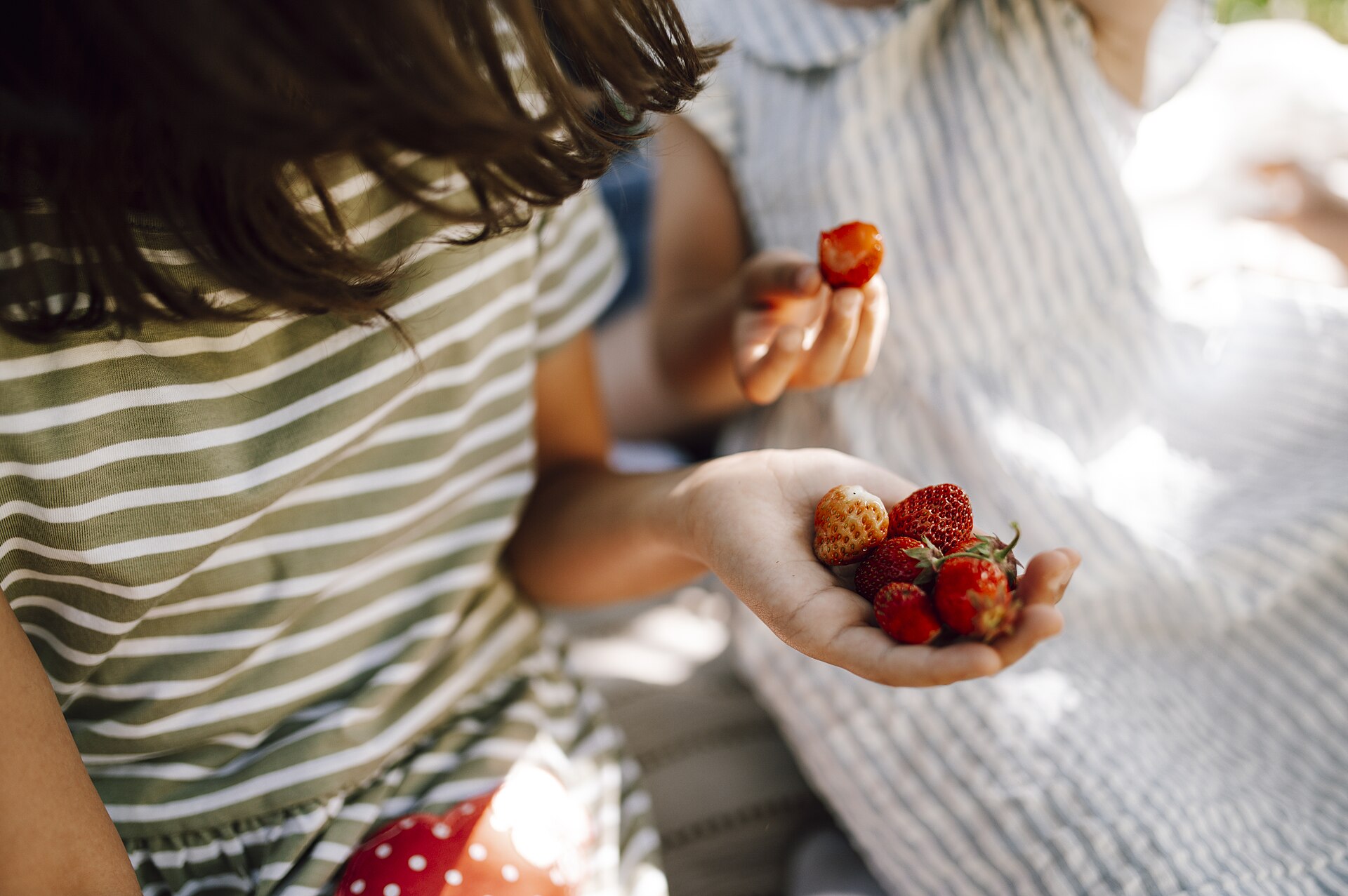 摘んだいちごを掲げる2人の子ども。