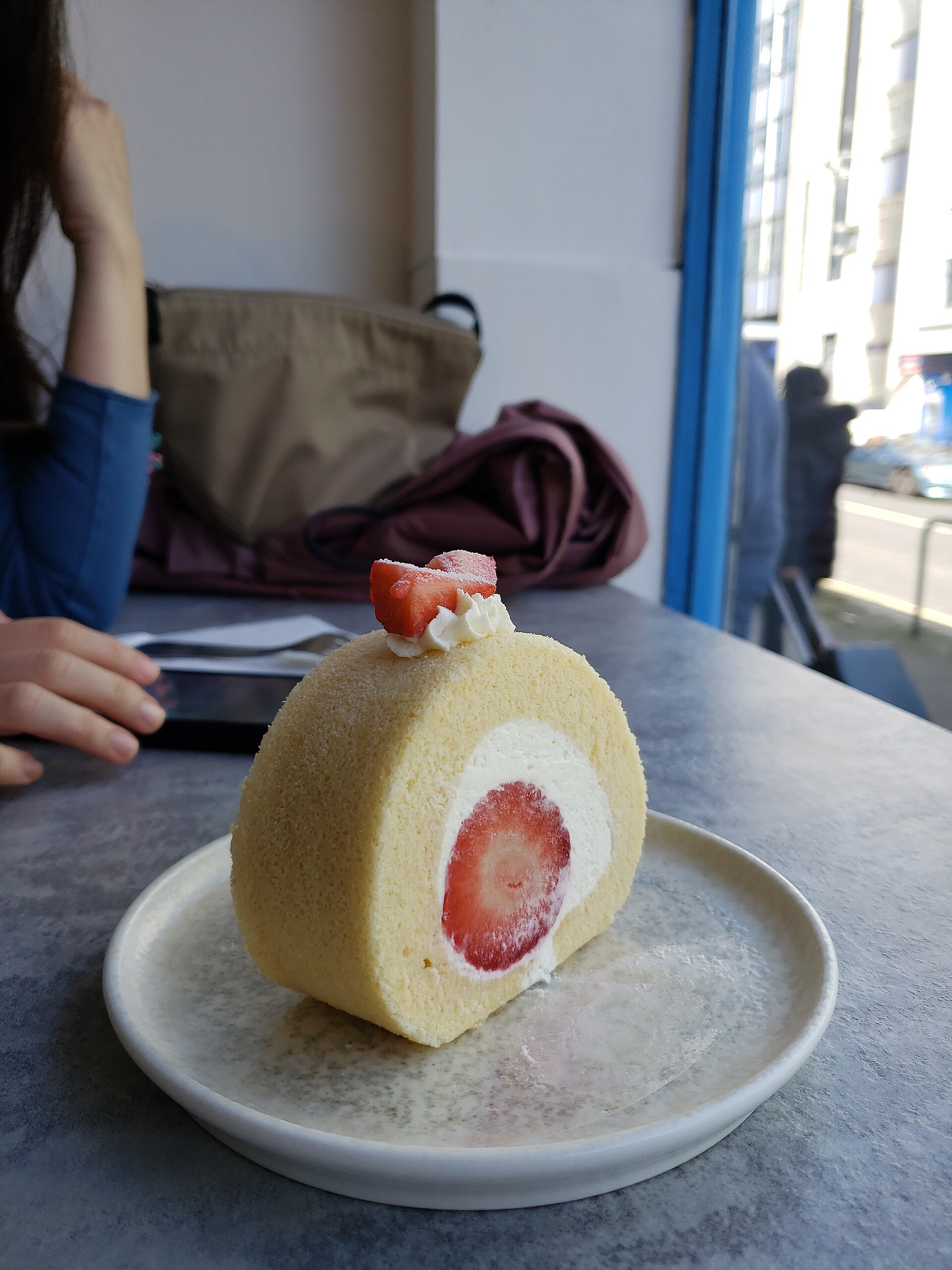 お皿にのせたいちごロールケーキのひと切れ。