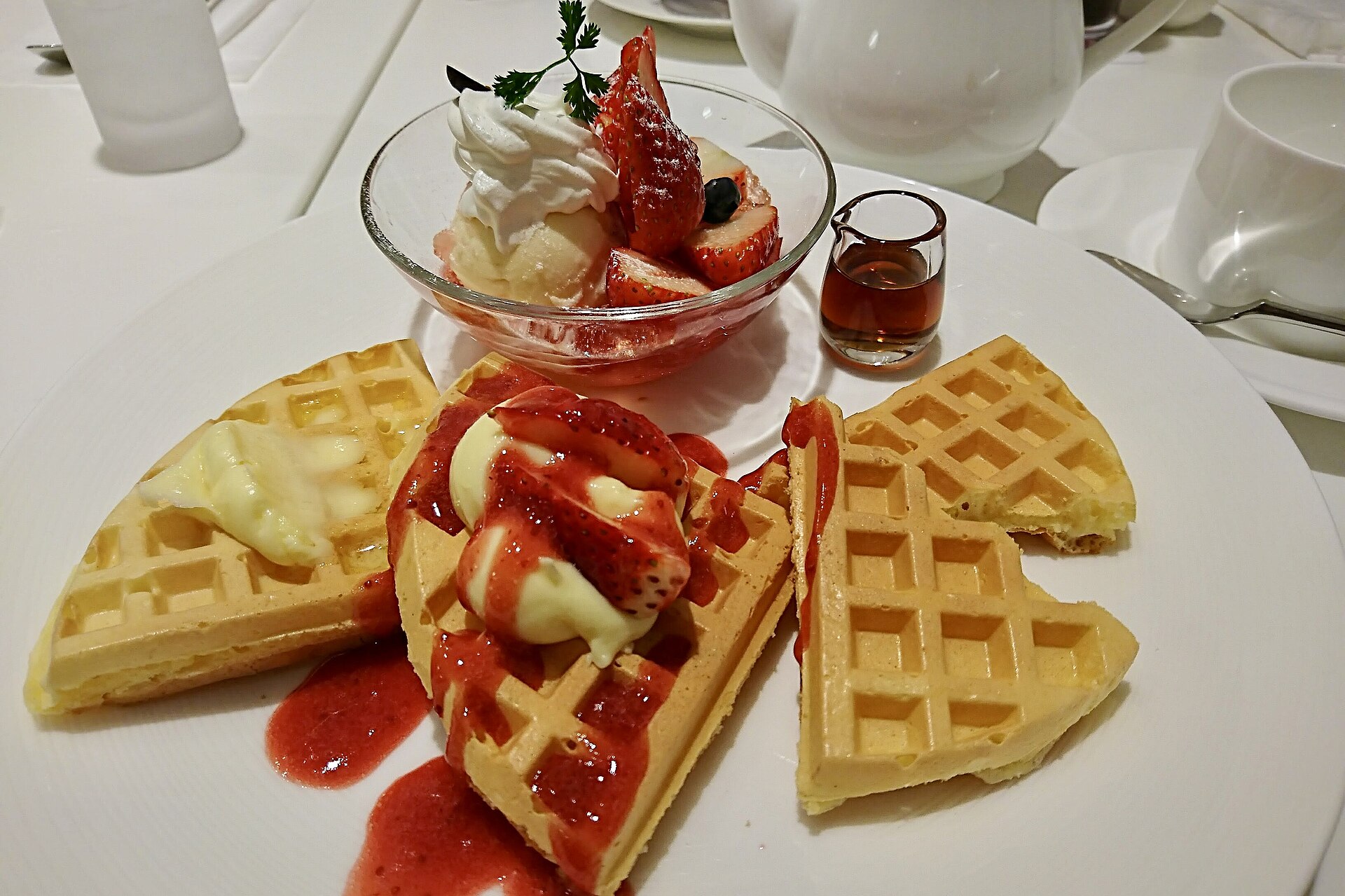 クリームとソースを添えたいちごワッフルのプレート。